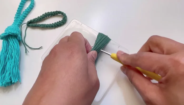 Insert the hook near the wrapped yarn, gather the yarn loops, and secure with a separate piece of yarn. Tie several knots to secure.