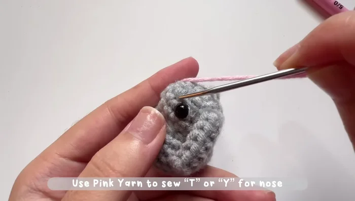 Add a nose using pink yarn by sewing a 't' or 'Y' shape between the eyes.