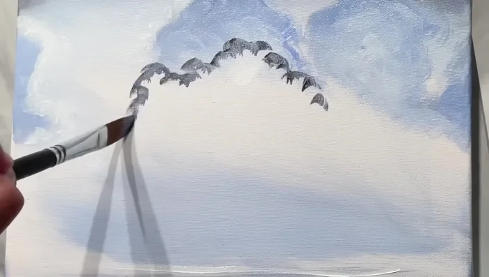 Saturate certain cloud areas with heavier paint to add depth and contrast, ensuring the clouds aren’t completely flat. Use a hint of white and blue to prevent clouds from looking completely black.