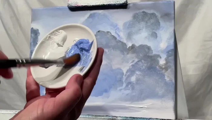 Saturate certain cloud areas with heavier paint to add depth and contrast, ensuring the clouds aren’t completely flat. Use a hint of white and blue to prevent clouds from looking completely black.