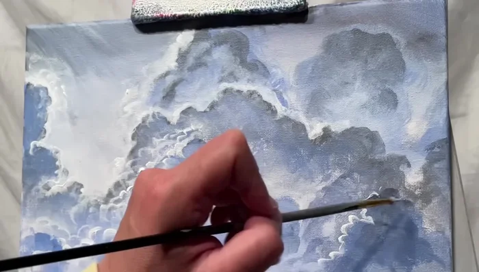 Continue layering clouds with varying shades and intensities, creating depth and realism.