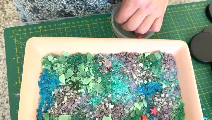 Embed marine life: Carefully place marine life embellishments (fish, shells, anemones) into the glass layers.