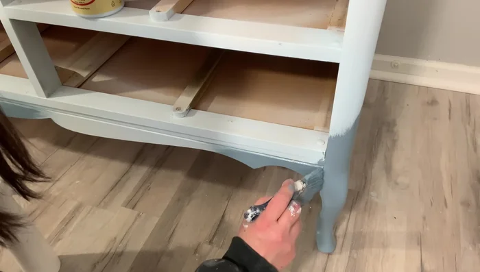 Shade with Dixie Belle Dusty Blue, creating a gradient effect from darker at the bottom to lighter at the top. Use a damp cloth to blend for a soft transition. Focus on the bottom and sides of the dresser, slightly blending upwards.