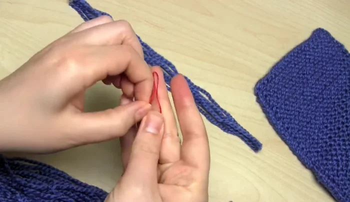 Remove the needle and thread. Put your fingers through the loop, grab the yarn ends, and pull them through to tighten.