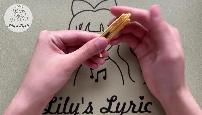 Wrap yarn around the whole branch. Apply glue to the end, wrap yarn around it, and cut the extra yarn. Adjust the shape. Repeat for a second flower, assembling with the longer branch and adding the leaf.