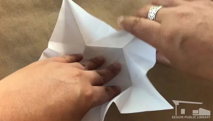 Press flat, flip over. Fold each point of the back pentagon toward the center, aligning with the peak.