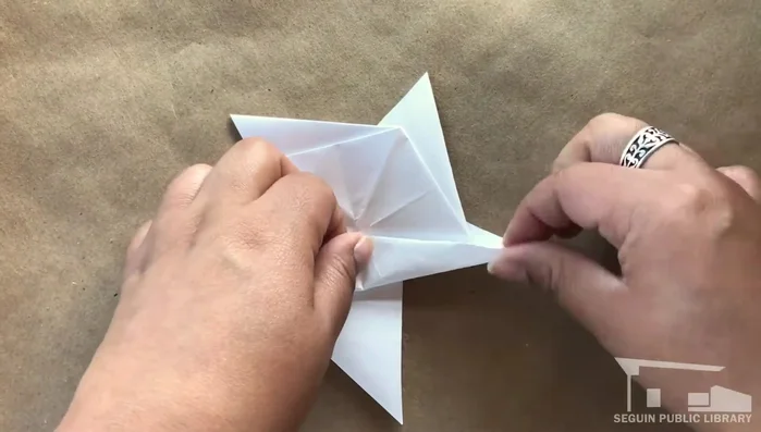 Press flat, flip over. Fold each point of the back pentagon toward the center, aligning with the peak.