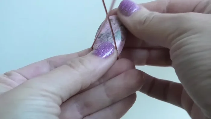 Curve the wires around the stone, keeping them flush against its sides and close together to avoid gaps.