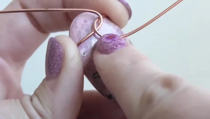 Curve the wires around the stone, keeping them flush against its sides and close together to avoid gaps.