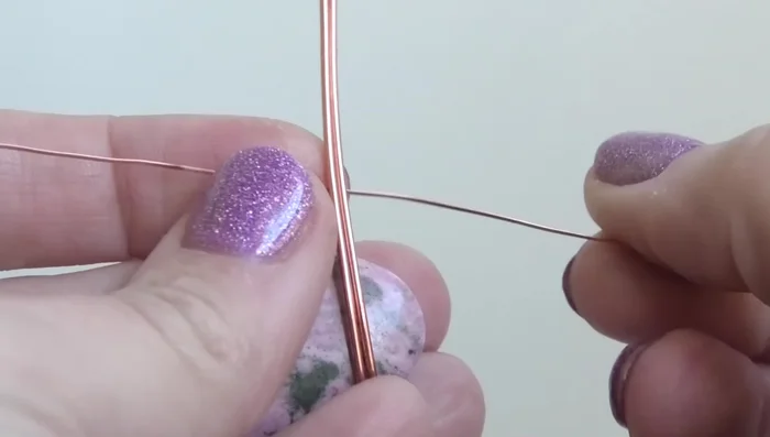 Bend the top wire upwards and the bottom wire downwards. Bend the top wire into a bail, ensuring it’s centered at the top of the stone.