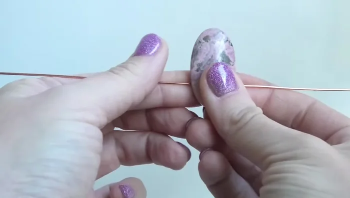 Curve the wires around the stone, keeping them flush against its sides and close together to avoid gaps.