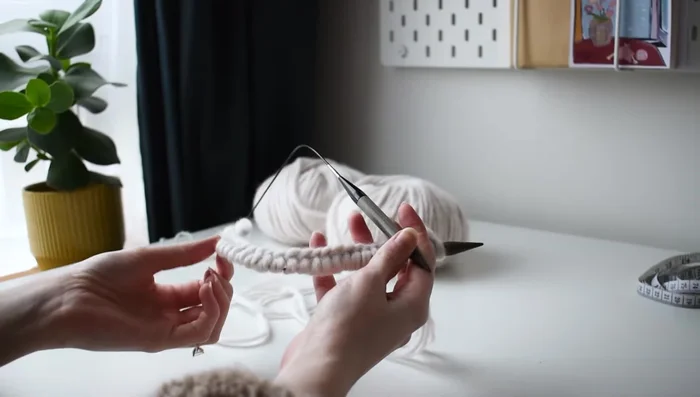 Join in the round using the basic method described in the video. (Looping together a scrap piece of yarn in a different color to mark the round.)