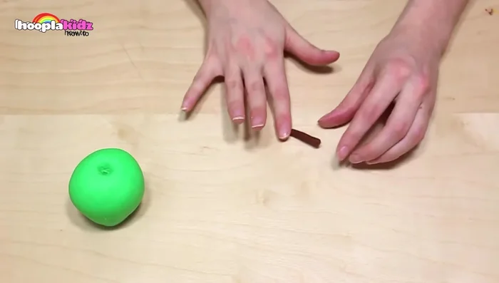 Make cherries: Roll two balls of dark red Play-Doh. Create indentations at the top. Roll a thin strip of dark green Play-Doh, fold it in half, and insert each end into the cherry tops. Add a leaf.