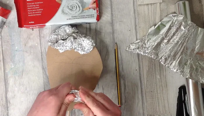 Gradually build up the structure using tin foil and hot glue, sculpting the basic shape of the face (brow bones, nose, chin, cheeks). Refer to references (mirror, photos, sketches) as you go.