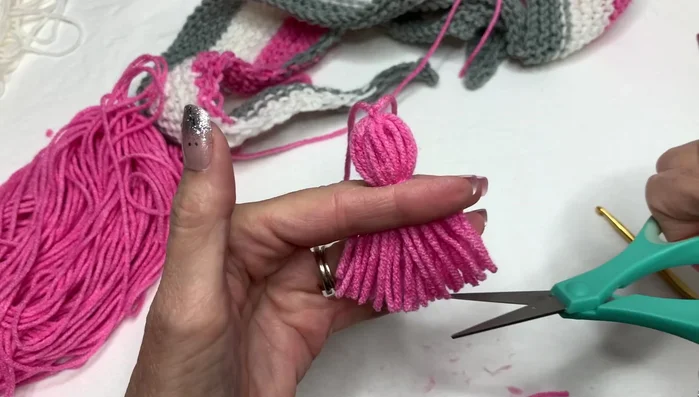 Attach tassels to the ends of the scarf by weaving the yarn through the edge stitches and securing.