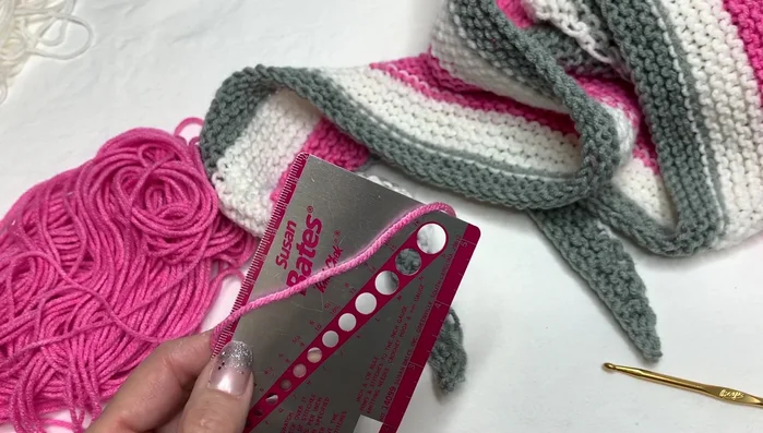 Attach tassels to the ends of the scarf by weaving the yarn through the edge stitches and securing.