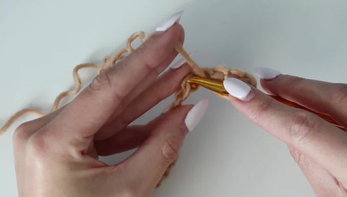 Row 1 (continued): When you reach the end, perform a decrease (double crochet two together) by skipping three chains between the two double crochets.