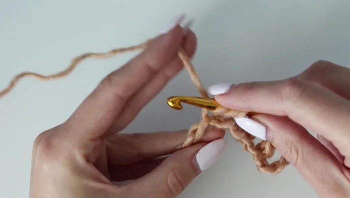 Row 1 (continued): When you reach the end, perform a decrease (double crochet two together) by skipping three chains between the two double crochets.