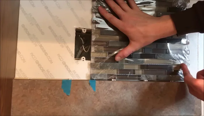 Cut the mesh backing of the tile to separate sections for easier installation around outlets and switches.