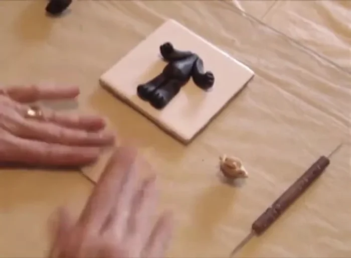 Use the pasta machine to create a thin sheet of ecru clay. Cut an egg shape and place it on the bear's body to form the belly.