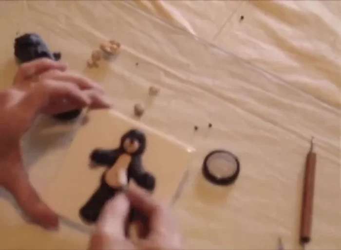 Add blush to the belly for color. Make two small balls of black clay for ears and attach them to the head, shaping them with the stylus.