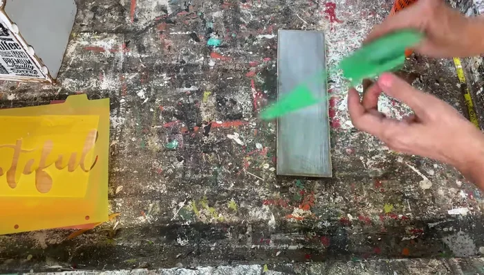 Lightly spray the back of the stencil with spray adhesive (optional, but recommended for better adhesion).