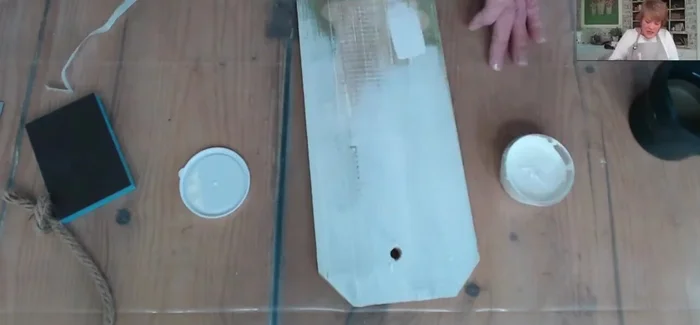 Paint the tag with a light-colored base coat to cover the previous design and create a light background for the decoupage paper.