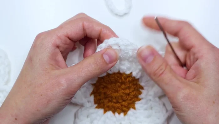 Attach flowers to the chain by using a yarn needle to sew them on securely, creating a knot.