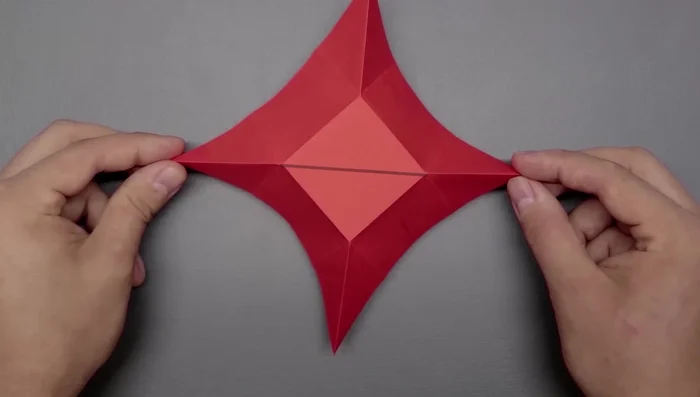 Create two new folds on the right side by bringing the corner to the left side of the middle square, and repeat on the left side.