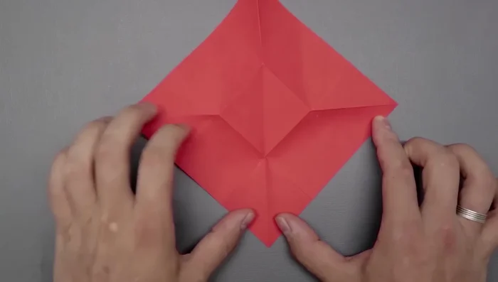 Create two new folds on the right side by bringing the corner to the left side of the middle square, and repeat on the left side.