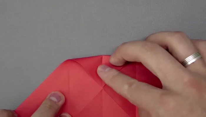 Fold the top corner and close. Now bring both sides to the middle; the paper should naturally assume the fish shape. 