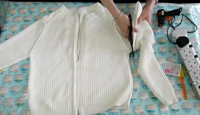 Cut across the top of the jumper to make it straight, removing the shoulder bits.