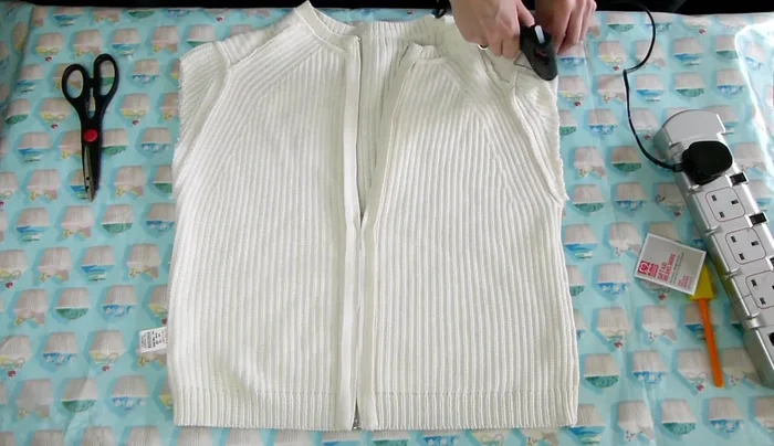 Cut across the top of the jumper to make it straight, removing the shoulder bits.