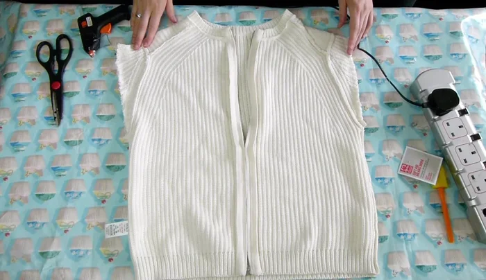 Cut across the top of the jumper to make it straight, removing the shoulder bits.