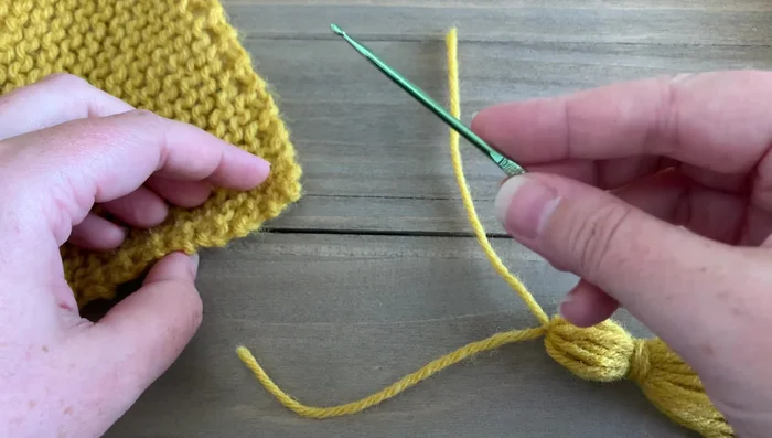 Attach tassels to the corners of the blanket using a crochet hook, weaving in the ends.