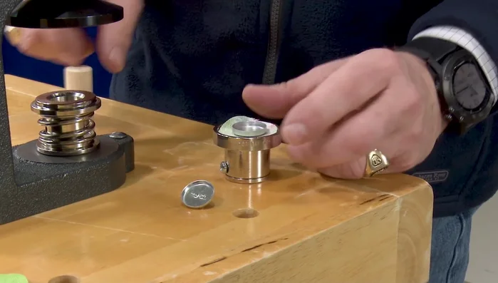 Use a dowel to press the button top and fabric into the concave portion of the die. Lift the outer collar.