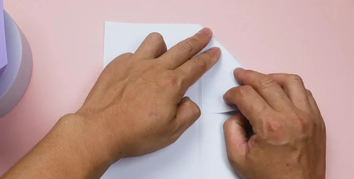 Unfold the paper. Fold the right side down to the center at a 45° angle, creating a diagonal line. Repeat on the left side. You should have a triangle at the top.