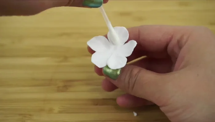 Shape the blossom: Use a small round object to sculpt the petals, twist or bend them, and snip off tiny triangles at the petal ends.