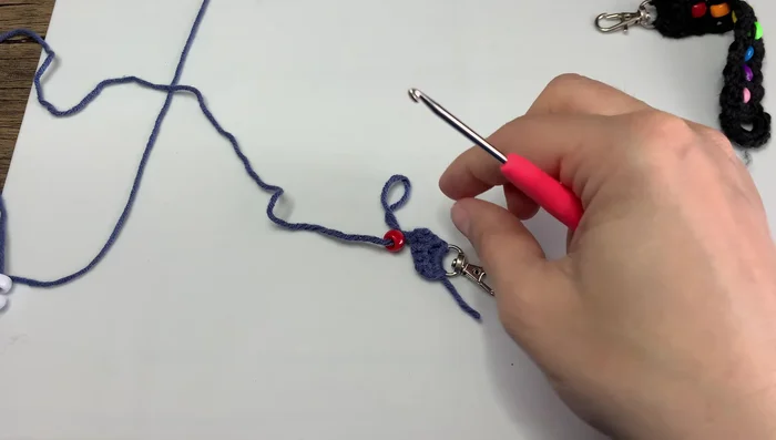 Crochet around the bead, working under the V-shape of the stitches.