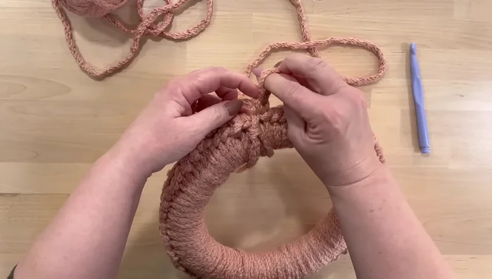 Finish the crochet. Once the wreath is fully covered, fasten off the yarn. For the final row, work five single crochet stitches, skip two, and repeat.