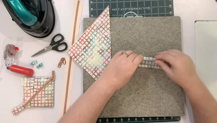 Make the handle: Fold the 3in x 5in piece lengthwise, press, fold in the long edges to meet in the middle, press, and fold in half again. Stitch along each edge.