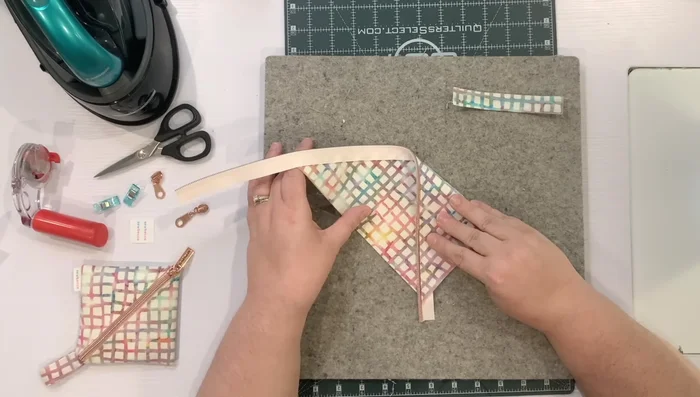 Fold the fabric into a pouch, creating a square shape, and press the corners. 