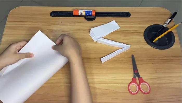 Fold another piece of paper in half and cut it. Fold one half in half, then again. Repeat on the other half.