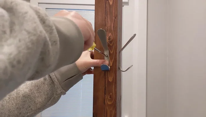 Attach the hooks using pre-drilled holes and screws.