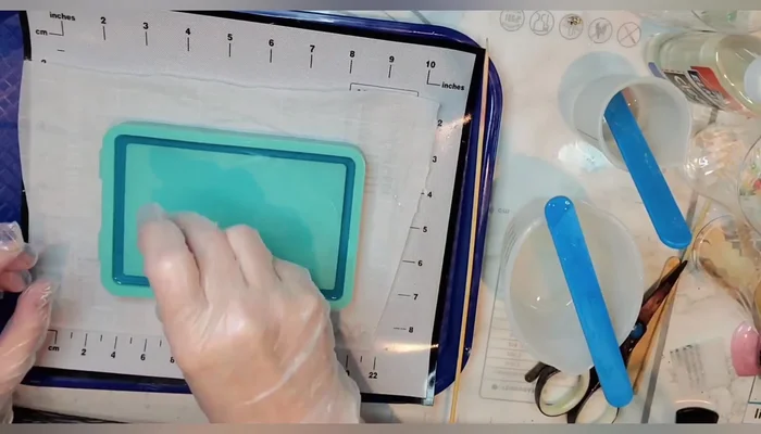 Arrange the mosaic tiles: Place the tiles on the resin layer, staggering colors and ensuring even spacing. Use a stick to adjust their positions.