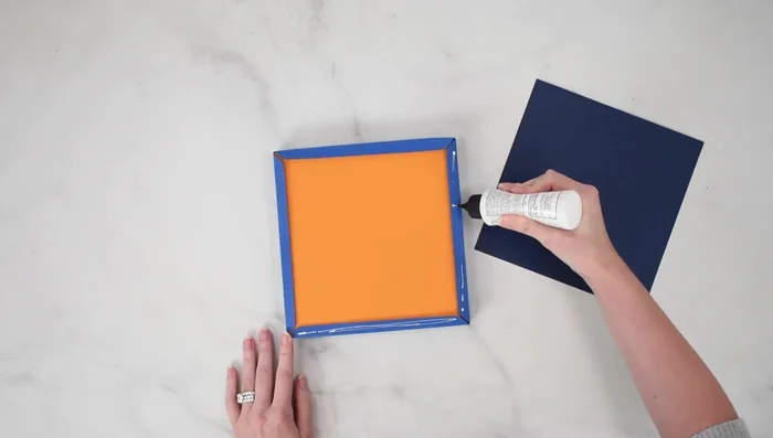 Apply glue to the edges of the cardstock frame's back piece and attach it to complete the shadow box.