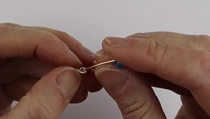 Bend the ends of the thinner wire to one side each, making sure the bead sits snugly within the 18 gauge wire.