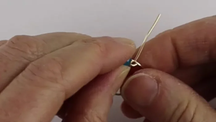 Bend the ends of the thinner wire to one side each, making sure the bead sits snugly within the 18 gauge wire.