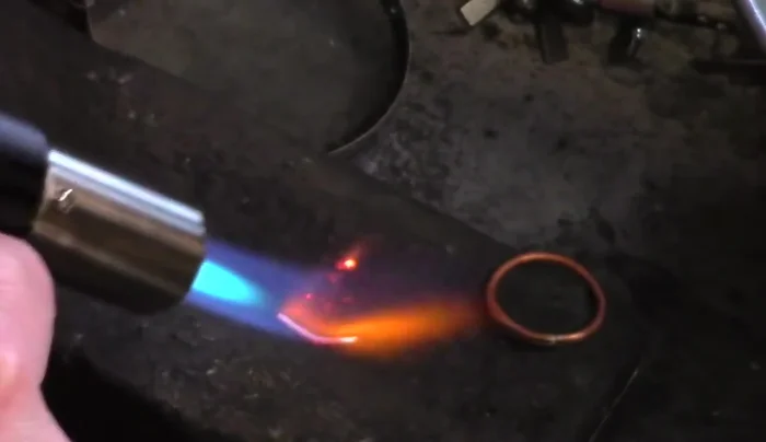 Attach the ball: Place the ball onto the ring where the solder joint is located. Apply more solder paste to the connection point. Heat the entire ring evenly to attach the ball, ensuring the solder flows and secures it to the band. Quench in water.