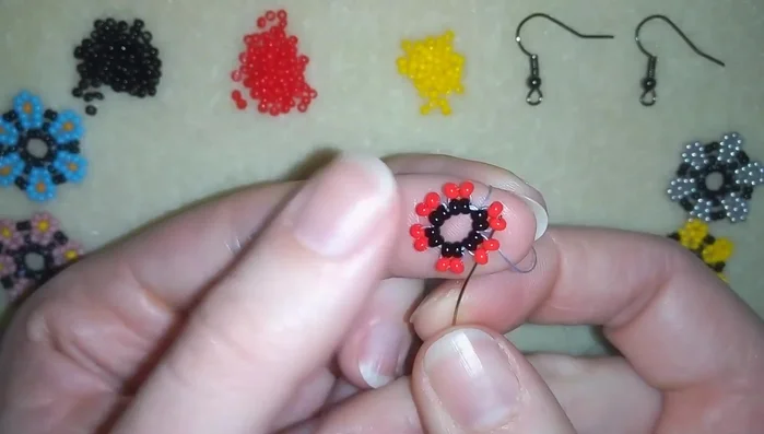 Continue adding the red-yellow-red bead sequence, interspersed with single black beads, to form the flower petals.
